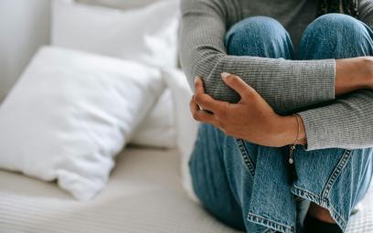 Woman sat down holding her legs against her chest