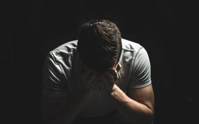 Man holding head in hands in darkness